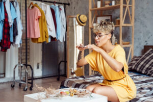 Young woman with dyed blonde hair and a yellow dress taking a photo of her meal for her side hustle while working in a fashion store