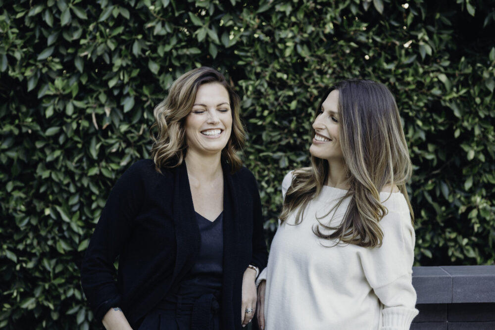 CGL's female founders, Hannah Genton and Noam Cohen, smiling in a garden landscape.