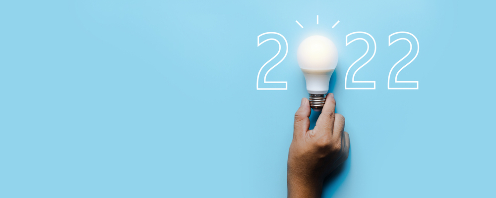Blue background with 2022 in the right hand corner, including a hand holding a light bulb in place of the 0 to demonstrate legal resolutions for 2022 are a good idea.