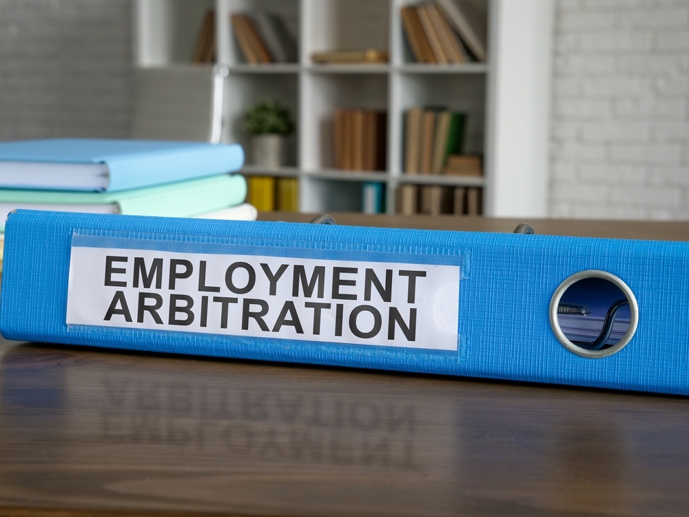 Blue folder on wooden desk with employment arbitration label on the side