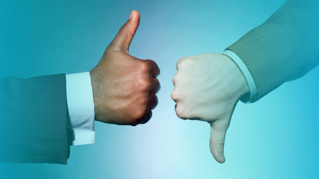 Photograph showing one employee with a thumbs up and another with thumbs down showing disagreement or employee conflict